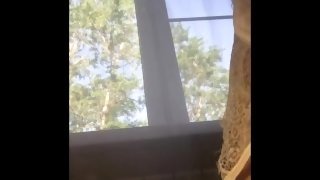 Girl sits on the window and inserts a tampon into her pussy during her period