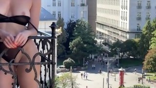 A woman undresses on a balcony in the city center. Public flashing.